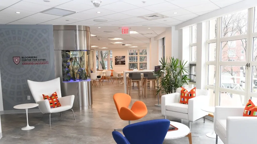 Bloomberg Center for Cities lounge at Harvard with aquarium pillar, modern seating, and campus windows